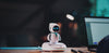Eilik sitting on the AI Station on a desk at night, ring light glowing